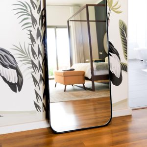 Detailed image of the Cosmic Mirror Large in Black leaning against a wall in a bedroom