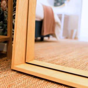 Close up of the Jupiter Mirror in a natural finish showcased in a bedroom setting